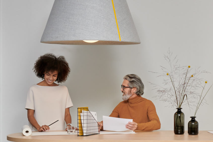 Mute Bell Lamp in office interior with tabletop beneath and people talking